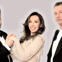 Kabaret Nowaki skład: uśmiechnięty mężczyzna w czarnym smokingu, kobieta w błyszczącej sukience i poważny mężczyzna w czarnym garniturze.