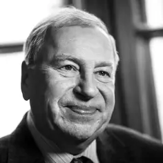 Uśmiechnięty Jerzy Stuhr, którego pochodzenie jest polskie, w czarno-białym portrecie.
