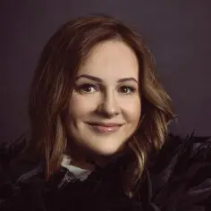 Uśmiechnięta Joanna z kabaretu w czarnych piórach, gotowa na występ.