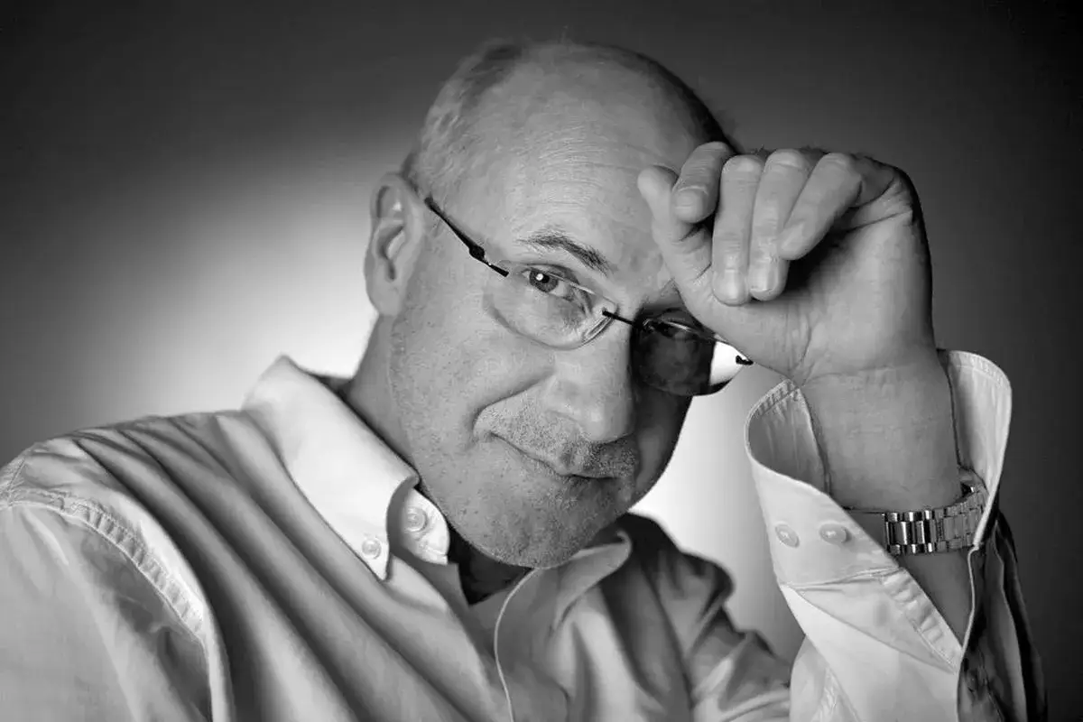 Piotr Machalica na co zmarł? Czarno-białe zdjęcie aktora w okularach, z ręką na czole, w białej koszuli.