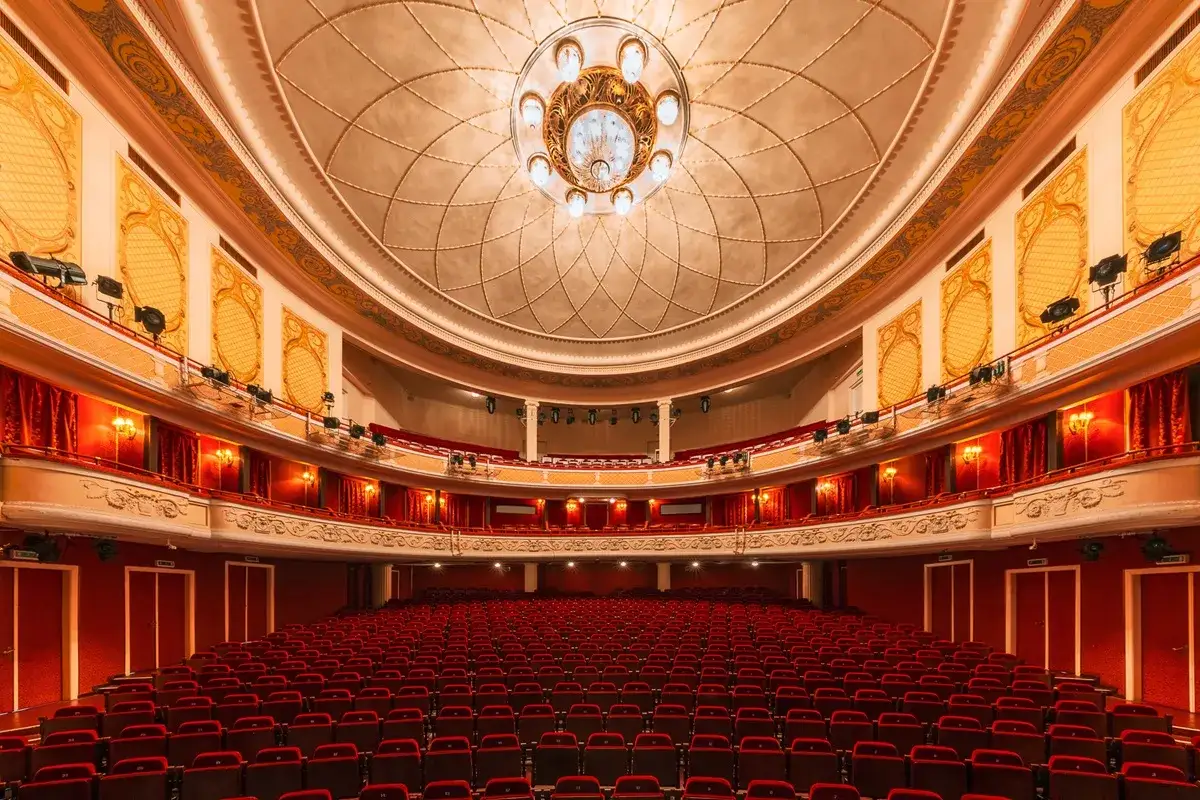Wnętrze teatru z czerwonymi fotelami i bogato zdobionym sufitem, gotowe na wspaniałą performance.